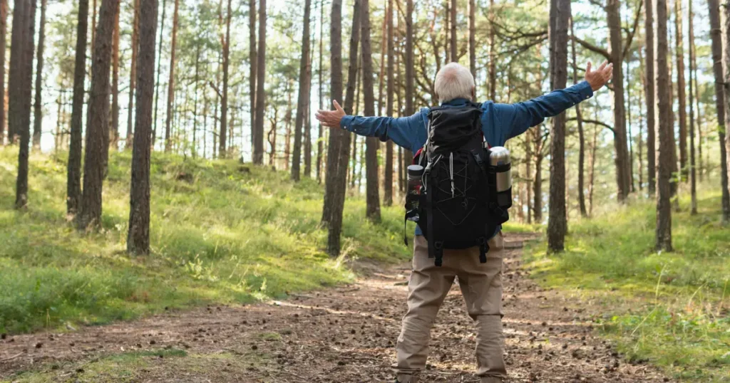 Batran in padure care sta cu mainile larg deschise