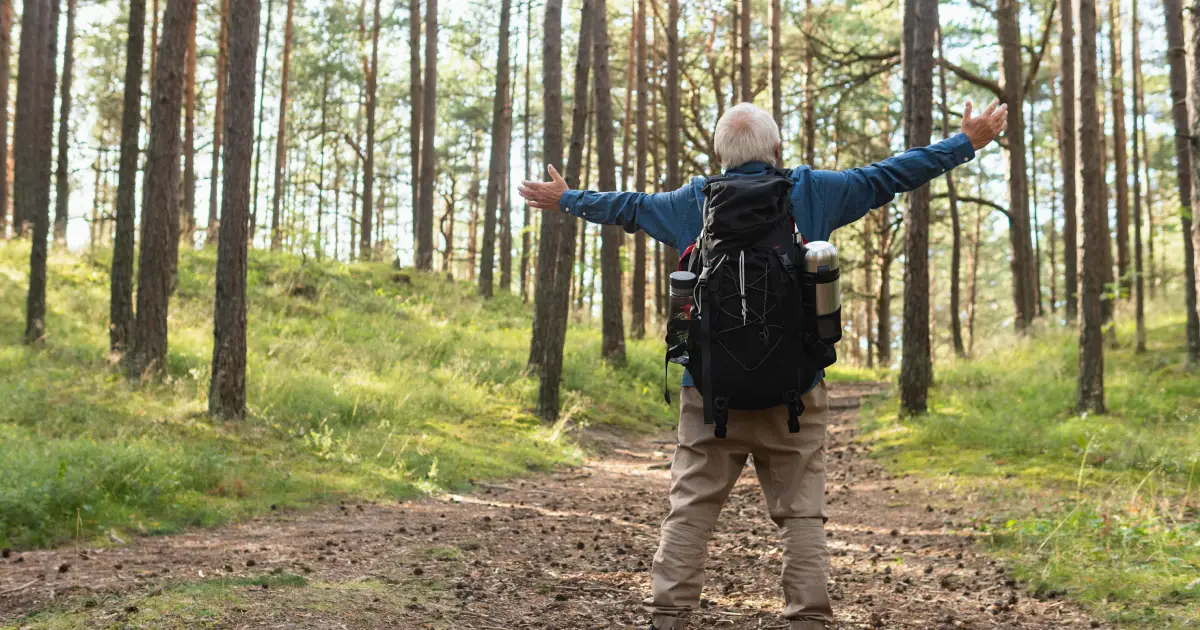 Batran in padure care sta cu mainile larg deschise
