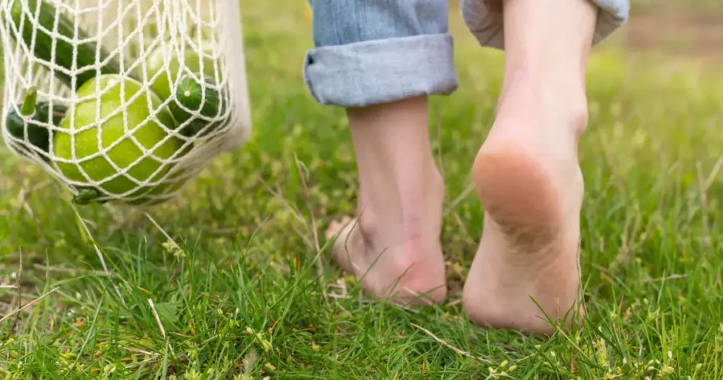 Femeie care paseste desculta pe iarba