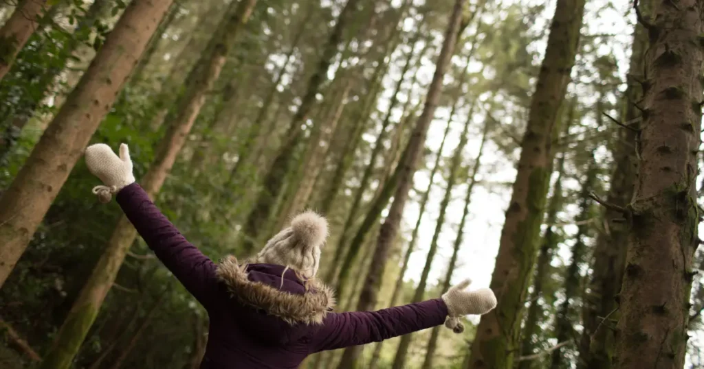 Fata in padure care sta cu mainile larg deschise