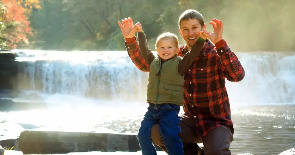 Tata si fiu pozand cu cascada in spate
