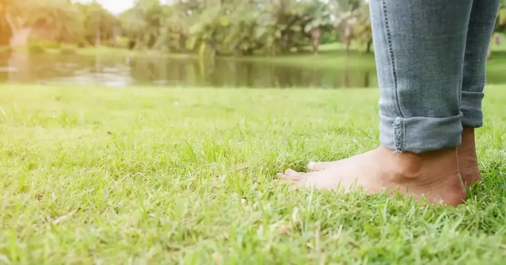 Femeie care sta cu picioarele goale pe iarba