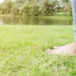 Femeie care sta cu picioarele goale pe iarba